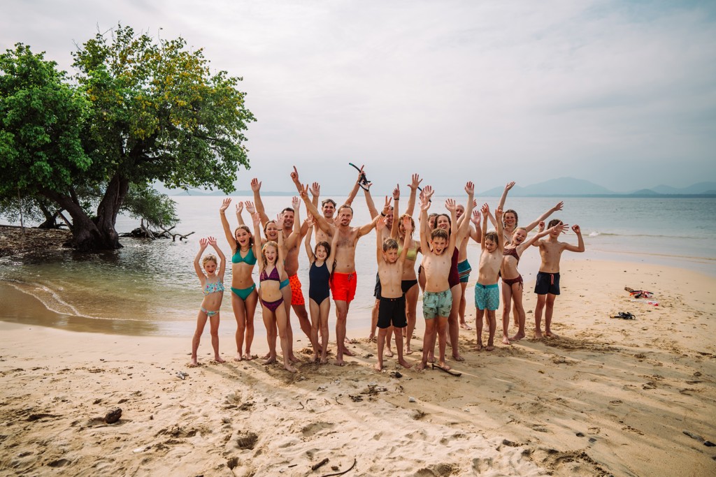 Groep gezinnen juicht op het strand tijdens Familiereis Thailand Chill & Adventure.