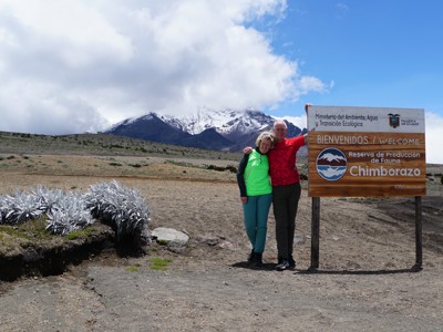 Reizigers bij het welkomstbord van Chimborazo, met besneeuwde vulkaan op de achtergrond in Ecuador.