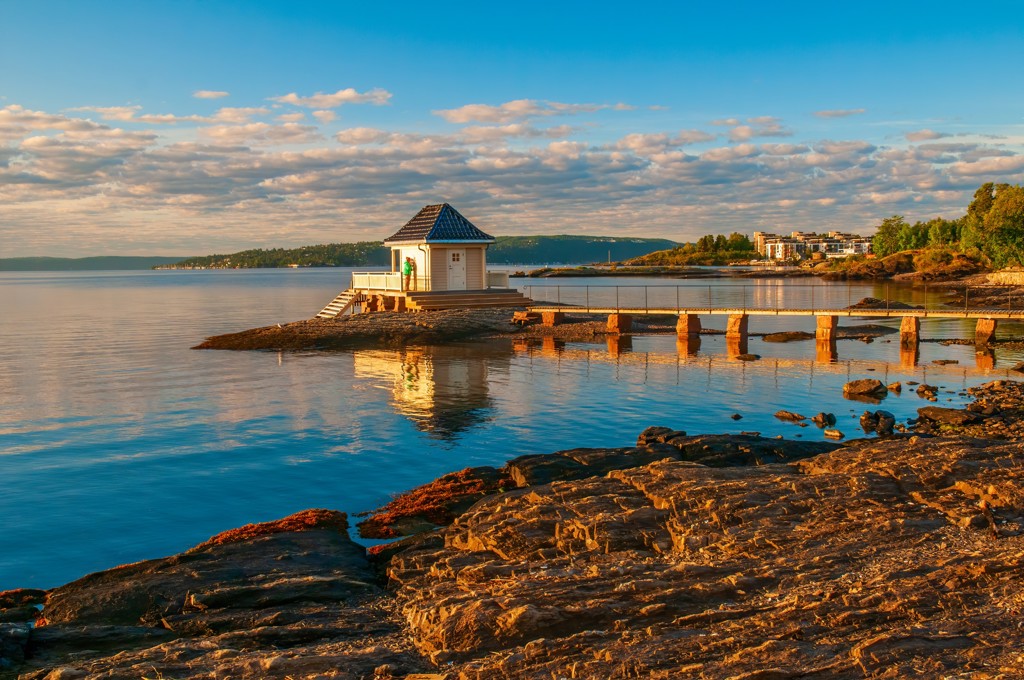 Steiger naar een klein paviljoen aan een rustige kust in Scandinavië bij zonsondergang.