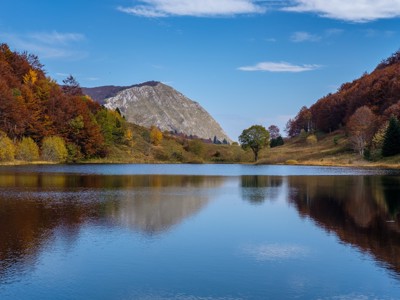Berglandschap met herfstbossen en een spiegelend meer tijdens de wandelvakantie in Bosnië & Herzegovina.