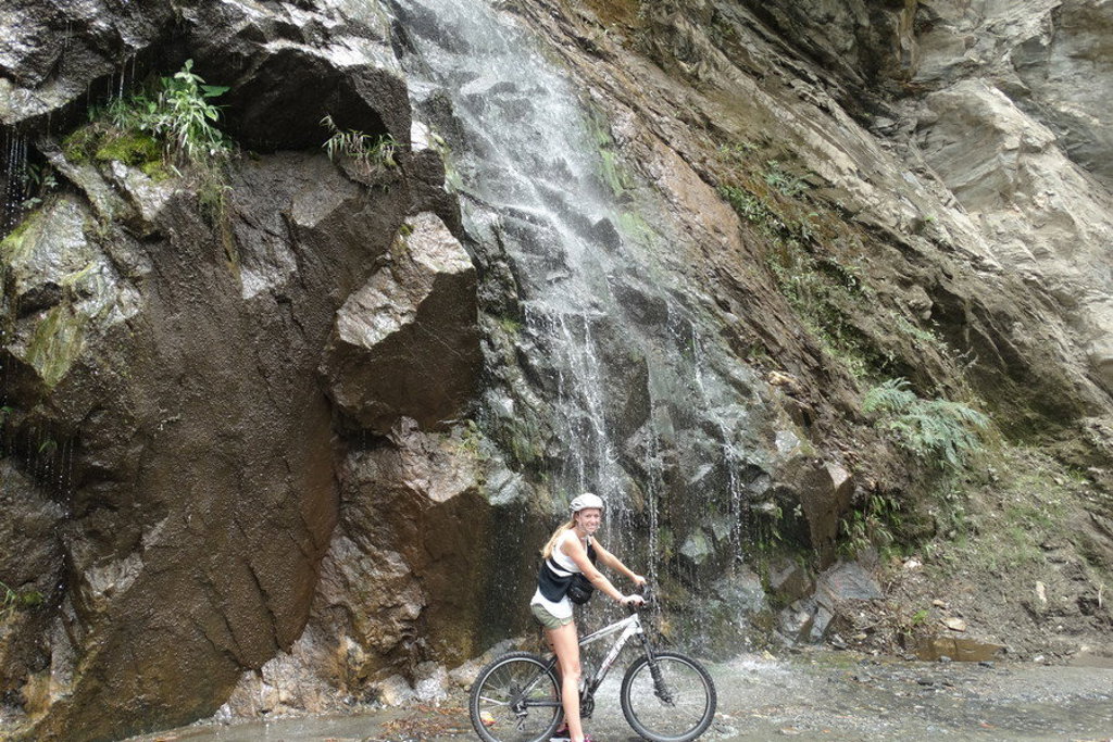 Fietser bij een waterval langs een rotswand tijdens de groepsrondreis Ecuador Hoogtepunten.