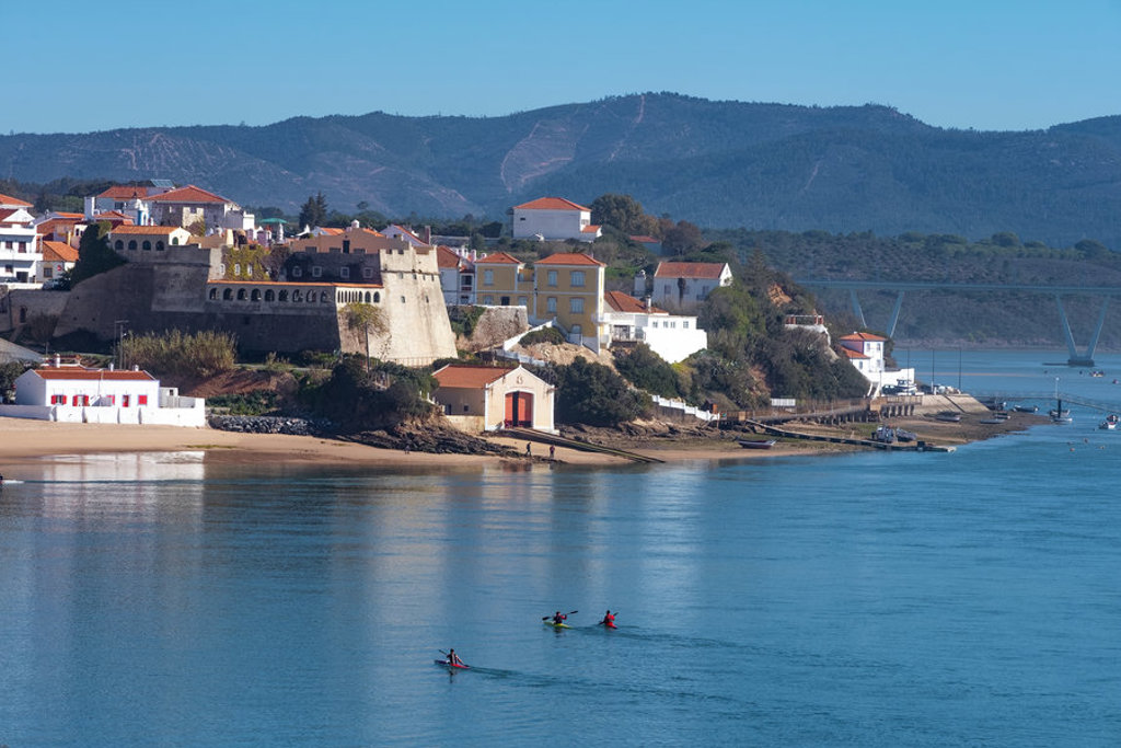 Kustplaatsje aan het water in Portugal, met vesting, witte huizen en kajakkers bij de Costa Vicentina.