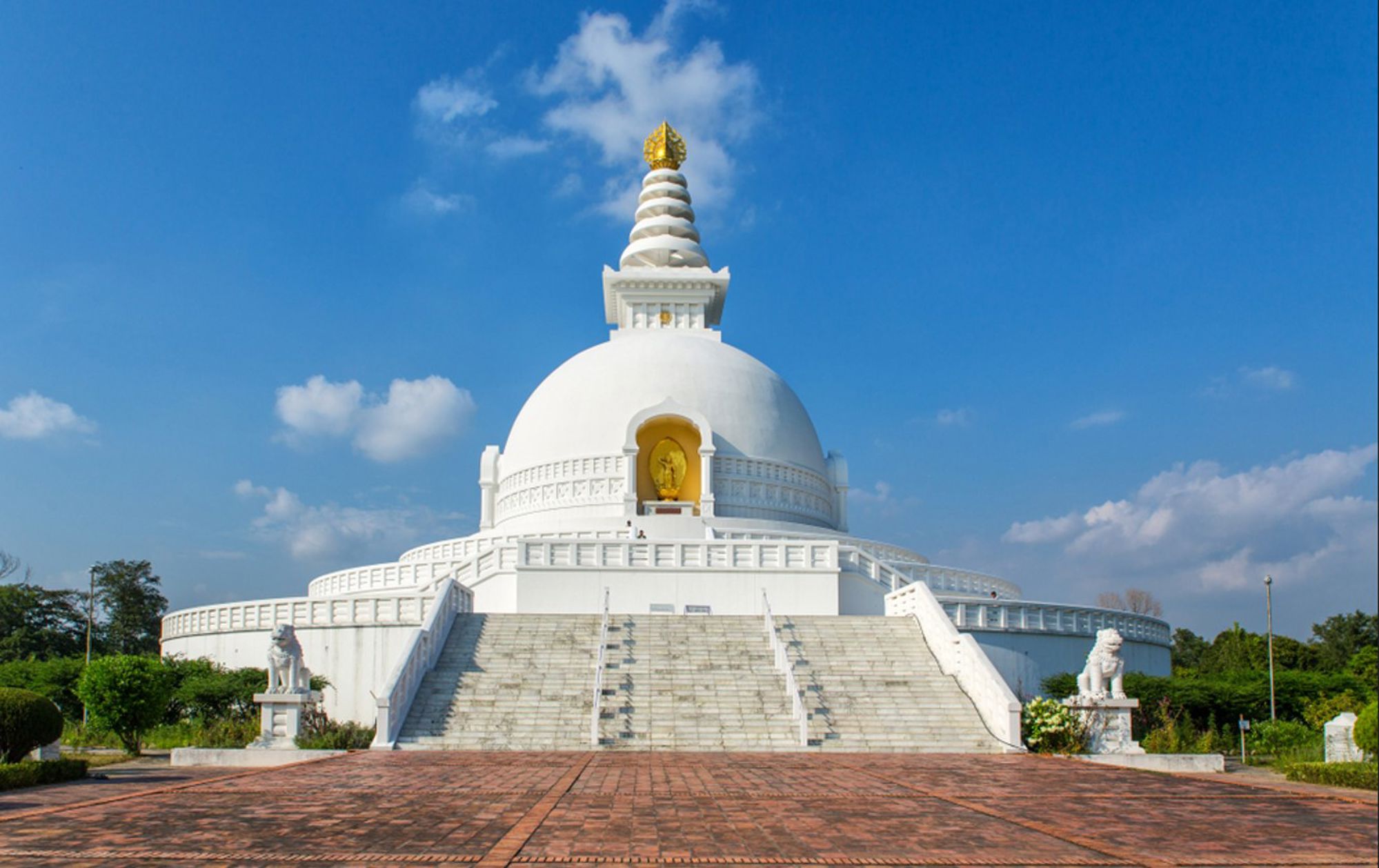 Witte World Peace Pagoda in Lumbini, Nepal, met gouden top onder een blauwe lucht.