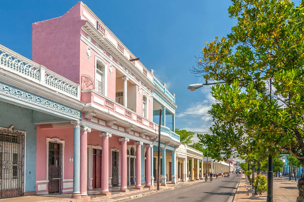 Pastelkleurige gevels met zuilengalerij langs een straat in Cuba, tijdens een groepsrondreis Cuba.
