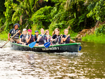 Groepsreis Costa Rica: kanoën op een rivier langs dicht regenwoud.