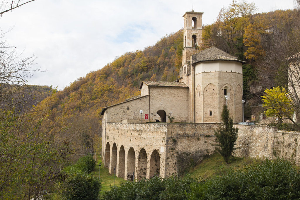 Klooster met klokkentoren in de Centrale Apennijnen, omringd door beboste heuvels in Italië.