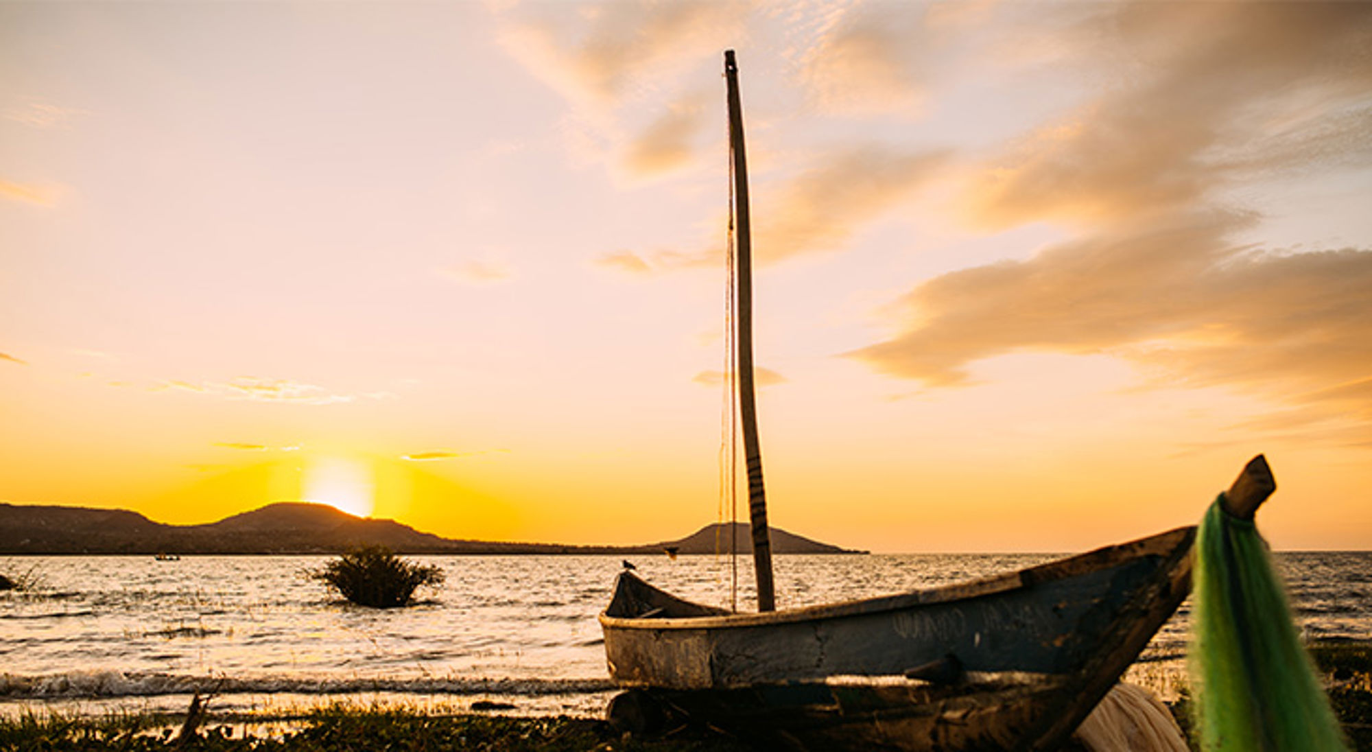 Zonsondergang bij het Victoriameer Houten dhow-boot aan de oever bij zonsondergang in Tanzania.