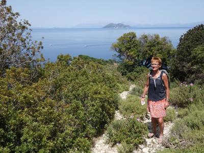 Wandelaar op rotsig kustpad op Evia, Griekenland, met uitzicht op de blauwe zee en eilanden.