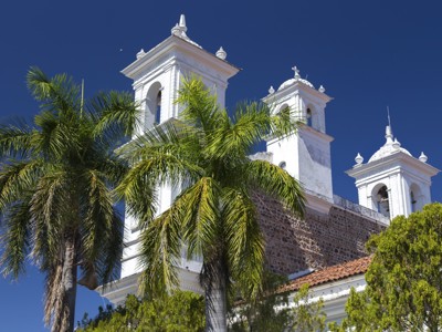 Witte kerk met klokkentorens en palmbomen langs de route Guatemala, El Salvador en Honduras.