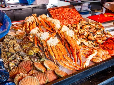 Seafoodkraam met koningskrab, garnalen, oesters en schelpdieren op een Noorse vismarkt.