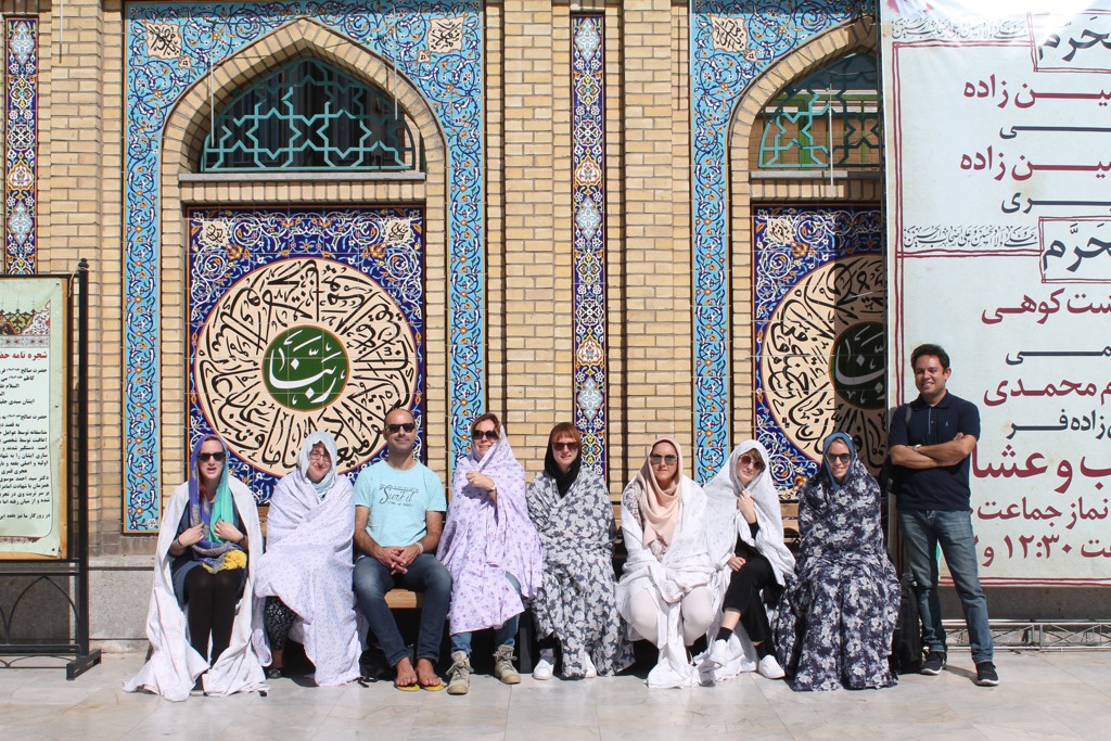 Reizigers bij een kleurrijk betegelde moskee tijdens een rondreis door Iran.