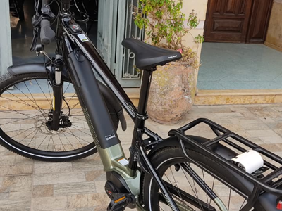 Zwarte e-bike met bagagedrager geparkeerd voor een gebouw.