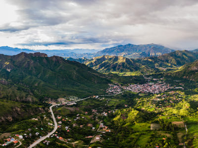 Panoramisch uitzicht op groene Andesvallei met dorp en slingerende weg in Ecuador.