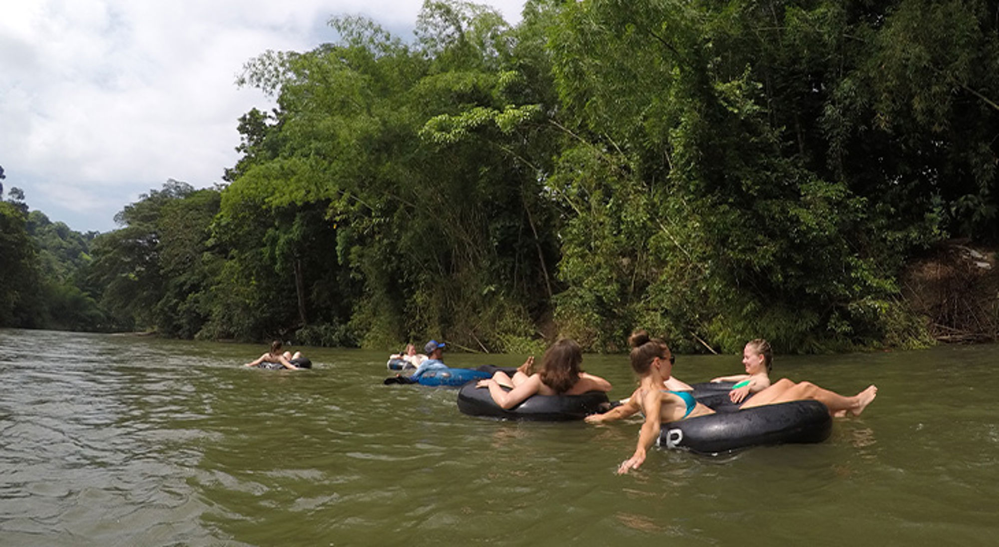 Tuben in Taironaka Groep reizigers dobbert op binnenbanden over een rivier langs dichtbegroeide jungle.