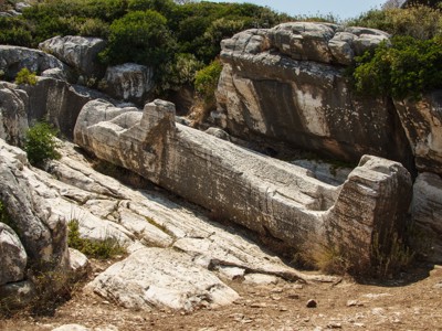 Oude marmeren sarcofaag tussen rotsen en struiken op Naxos tijdens de wandelvakantie.