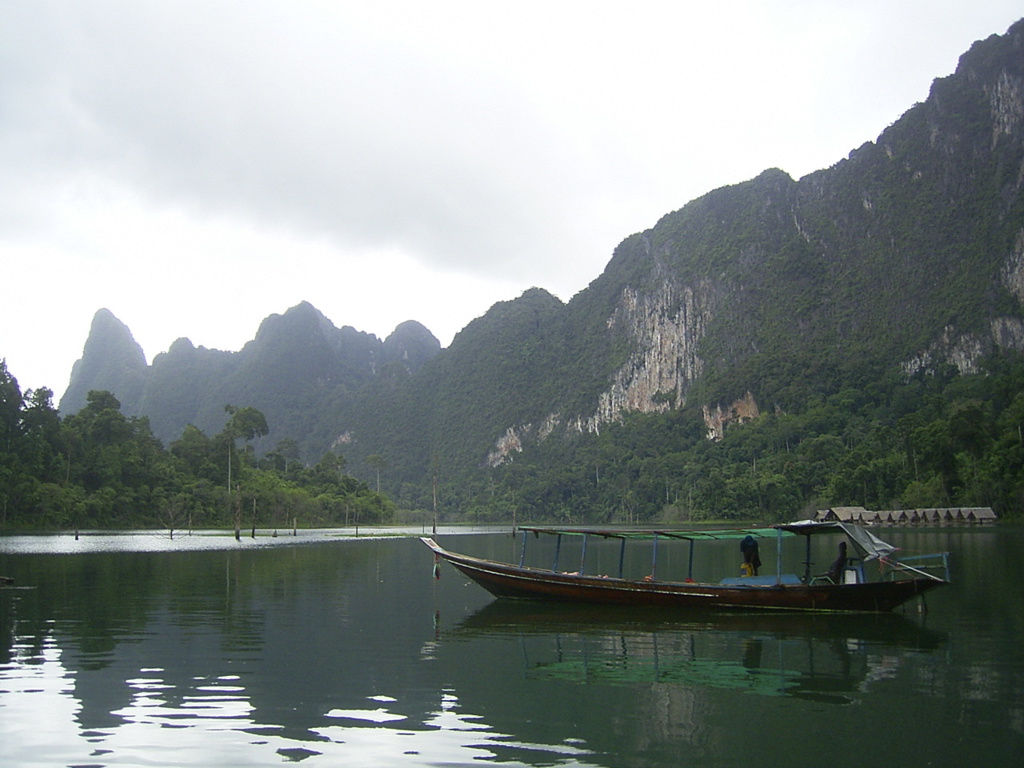Longtailboot op een rustig meer met groene kalksteenbergen in Thailand tijdens de rondreis Thailand Chill & Adventure.