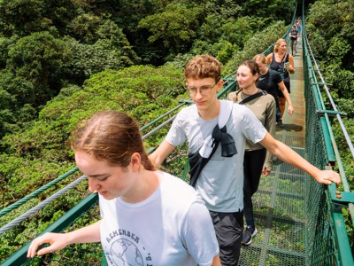 Groep wandelt over een hangbrug door het regenwoud in Costa Rica.