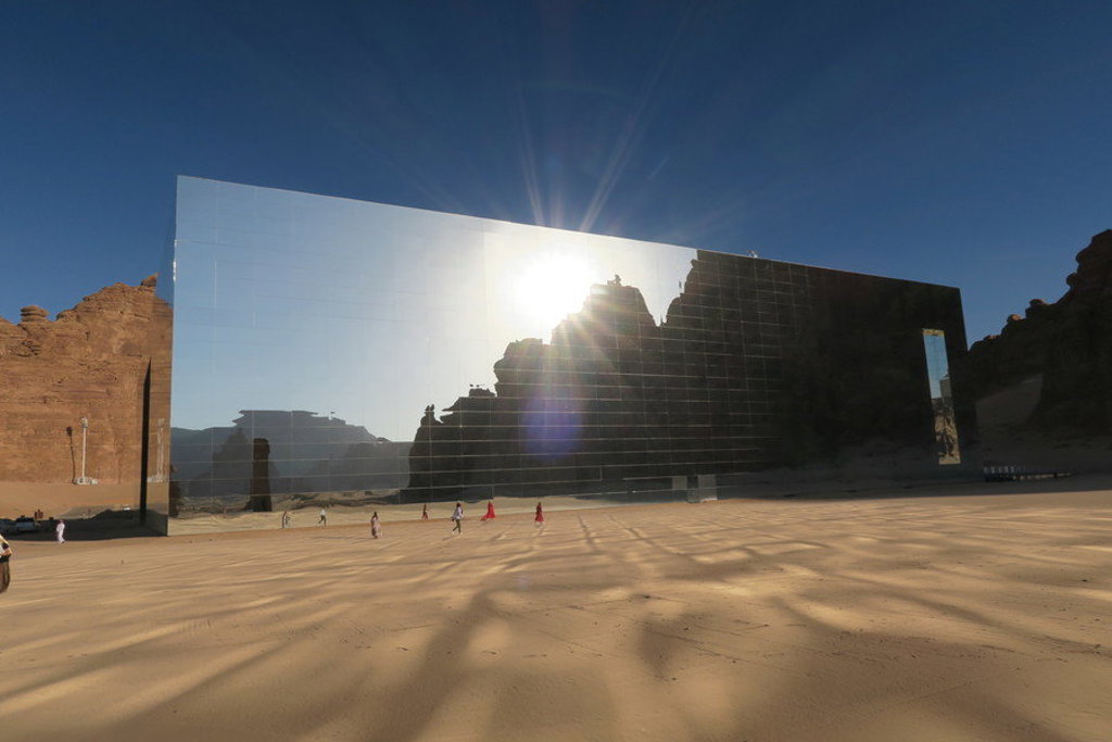 Maraya Concert Hall in AlUla, Saoedi-Arabië, met spiegelgevel en rotslandschap in de zon.