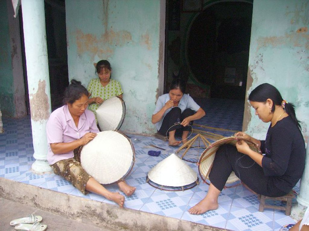 Vrouwen maken traditionele Vietnamese rijsthoeden tijdens een familiereis door Vietnam.