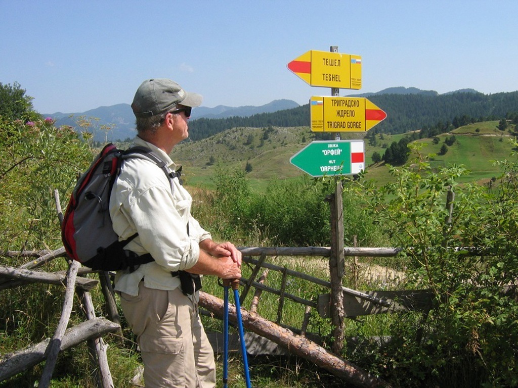 Wandelaar met rugzak bij wegwijzers in de Bulgaarse Balkan tijdens een wandelvakantie in Bulgarije.