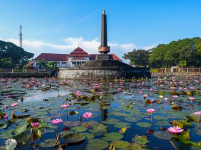 Monas-monument in Jakarta, met vijver vol roze waterlelies op de voorgrond.