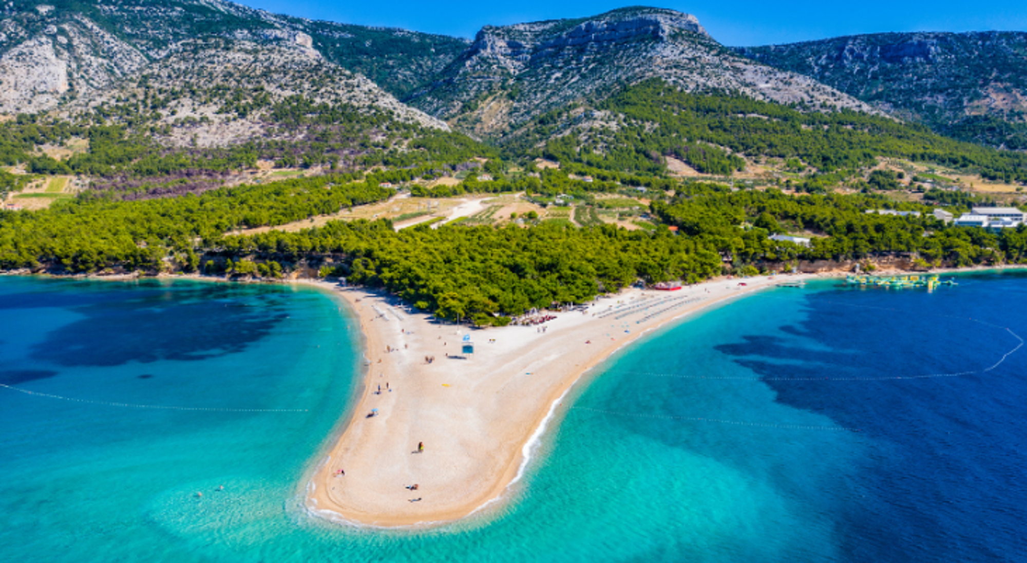 Zlatni Rat-strand op Brač met turquoise zee en berglandschap op de achtergrond.