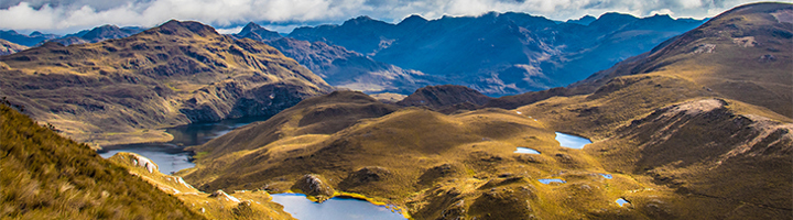 Berglandschap in Ecuador met hooggelegen meren onder een bewolkte lucht.