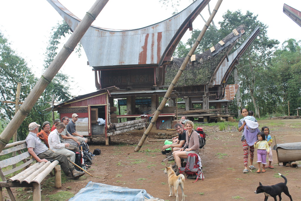 Reizigers bij een traditioneel Toraja-huis op palen in Sulawesi tijdens de groepsrondreis Kalimantan, Sulawesi & Molukken.