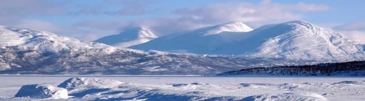 Besneeuwde bergen en bevroren landschap in Antarctica onder een heldere blauwe lucht.