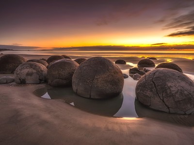 Moeraki Boulders op het strand van Otago bij zonsondergang, Nieuw-Zeeland.