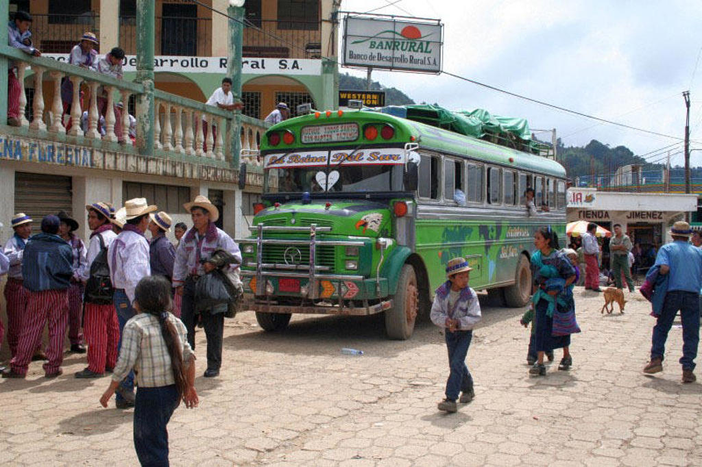 Groene bus op een druk plein langs de Pan-American Highway in Guatemala tijdens de groepsrondreis Trans-Midden-Amerika.