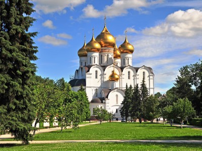 Witte Russisch-orthodoxe kathedraal met gouden koepels in een groen park onder een blauwe lucht.