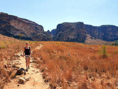 Wandelaar op zandpad door savannelandschap met rotsformaties in Madagascar.
