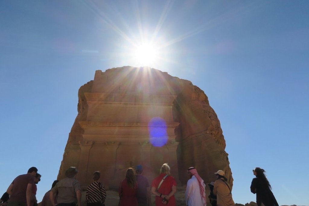 Reizigers bekijken een rotsgraf in Hegra (AlUla) tijdens een groepsrondreis door Saoedi-Arabië.