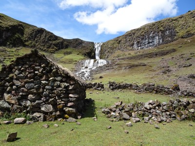 Waterval in de Peruaanse Andes met stenen hut en bergweide langs de Route Peru.