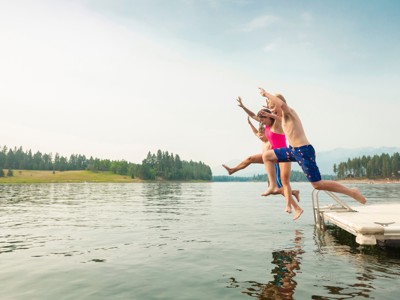 Kinderen springen vanaf een steiger het meer in tijdens de familiereis Écrins (camping) in Frankrijk.