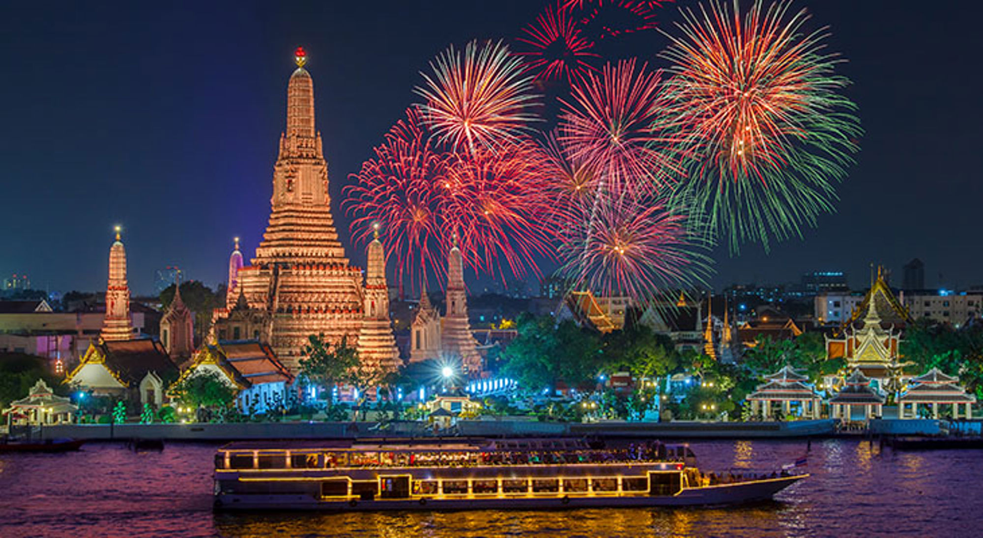 Eindejaarsviering in Bangkok Vuurwerk boven Wat Arun in Bangkok aan de Chao Phraya-rivier, met verlichte boot op het water.