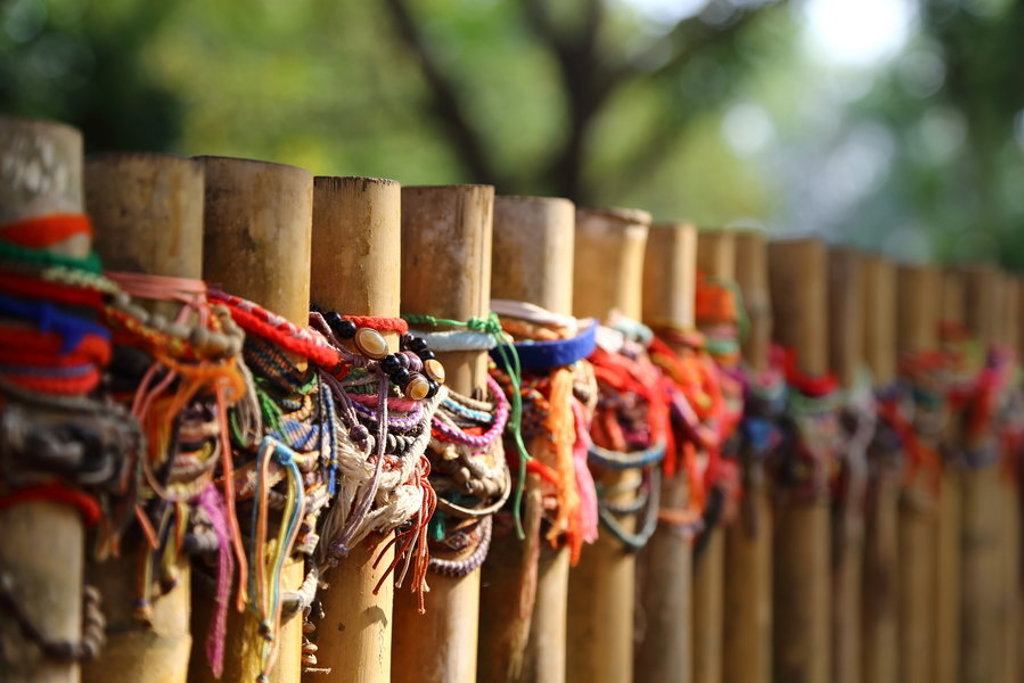Kleurrijke armbandjes en koordjes aan een bamboehekje tijdens een 22-35ers reis door Thailand, Laos en Cambodja.