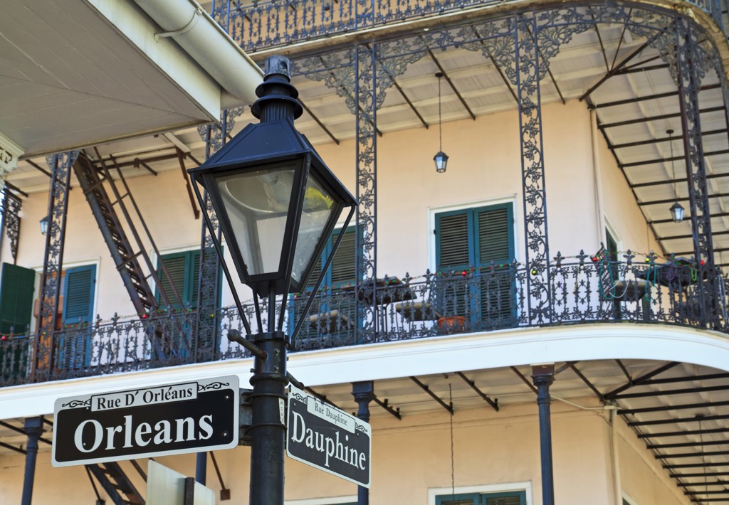 Straatnaamborden Orleans en Dauphine in de French Quarter van New Orleans, met balkon en gietijzeren hekwerk.