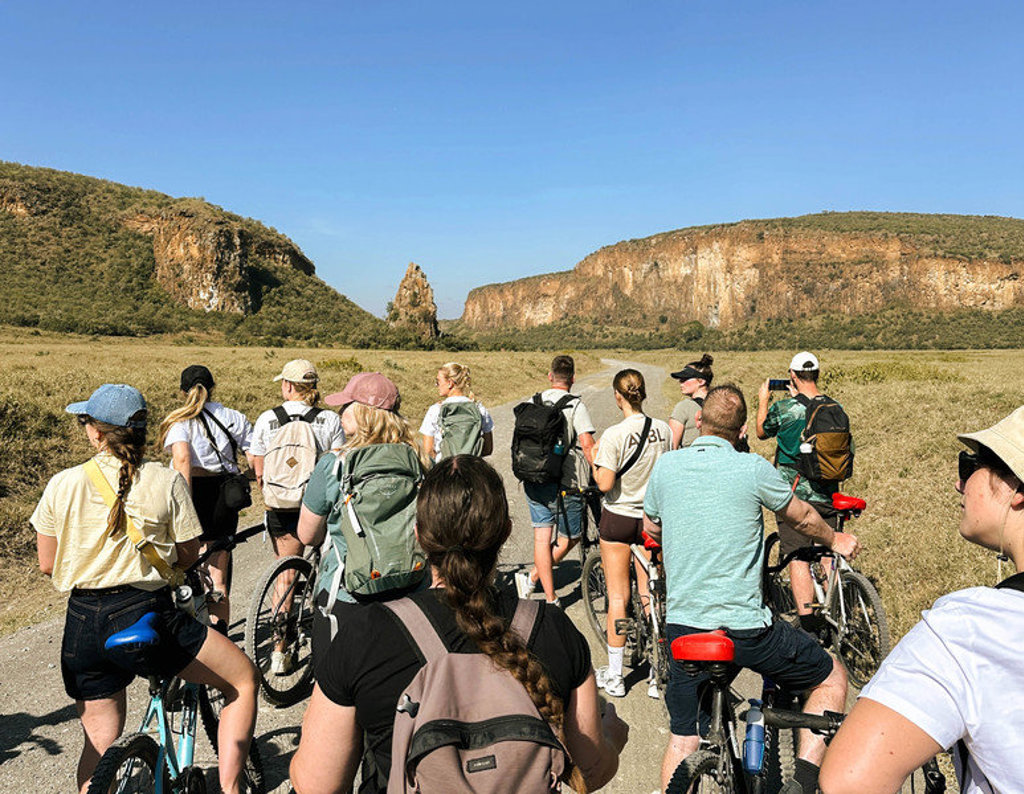 22-35ers groepsreis Kenia & Tanzania: groep fietsers op safari door savanne met rotsformaties.