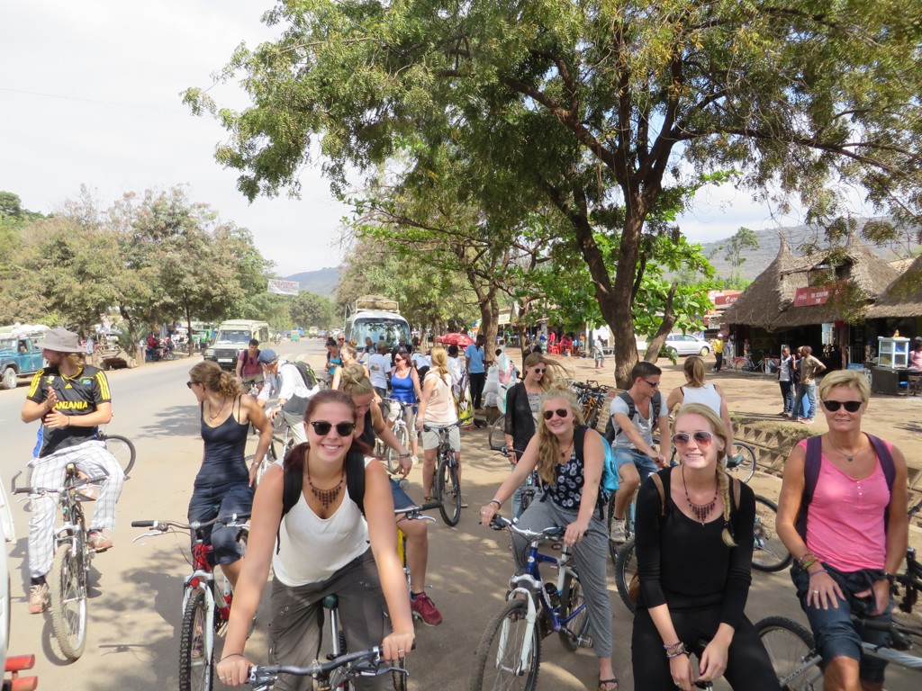 Fietsende reizigers in een dorp in Tanzania tijdens een familiereis Tanzania en Zanzibar.