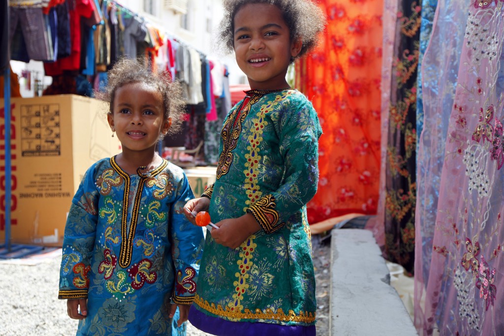 Twee lachende kinderen in kleurrijke kleding op een markt in Oman, tijdens een groepsrondreis Oman en Dubai.
