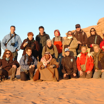 Groepsfoto van reizigers tijdens een groepsrondreis Jordanië, in de woestijn bij rotsformaties.
