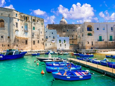 Haven van Monopoli in Puglia met blauwe vissersboten en witte huizen aan het water.