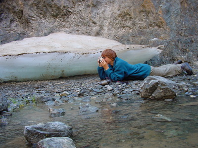 Reiziger fotografeert liggend langs een beek in een rotsachtige kloof tijdens de 23-daagse route door Mongolië.