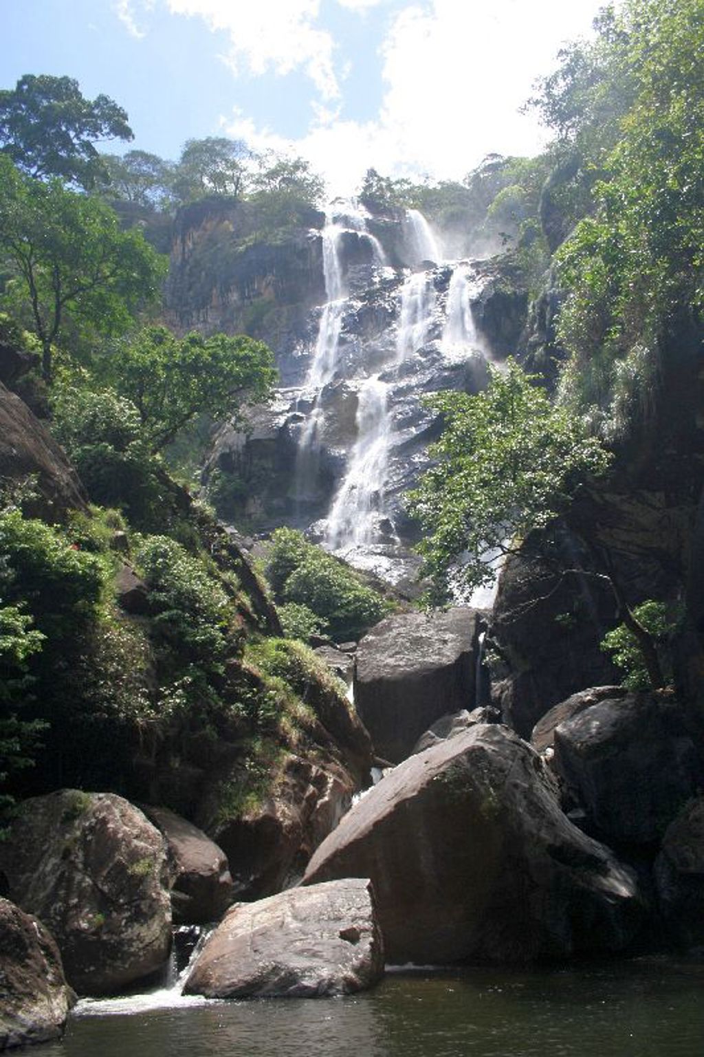 Waterval die in meerdere trappen over rotsen naar beneden stroomt, omringd door groen in Zambia, Malawi en Tanzania.