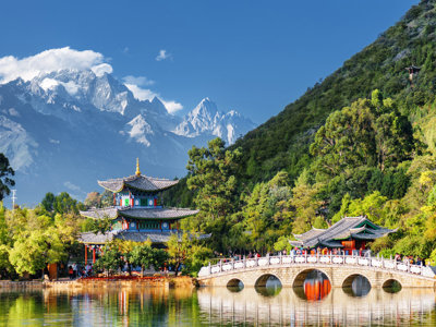 Pagode en stenen brug bij Black Dragon Pool in Lijiang, met besneeuwde Jade Dragon Snow Mountain op de achtergrond.
