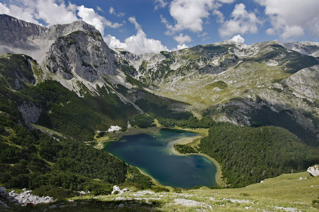 Berglandschap met groenblauw meer tussen ruige rotsen en groene hellingen in Montenegro.