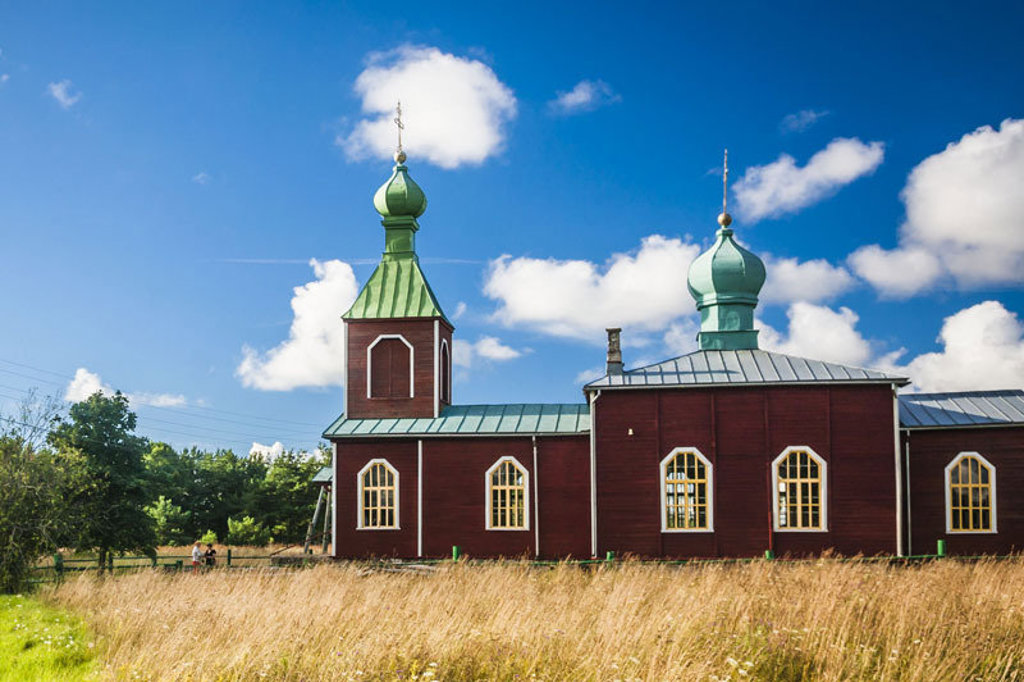 Houten kerk met groene koepels in Estland tijdens groepsrondreis Estland, Letland en Litouwen.