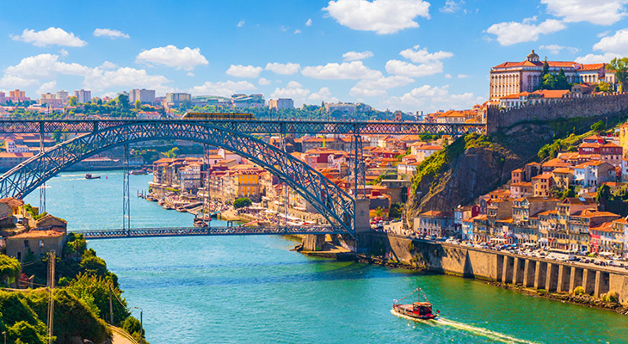 Ponte Dom Luis I-brug, oude stad, Porto Uitzicht op de Dom Luís I-brug over de Douro met de skyline van Porto en een boot op het water.
